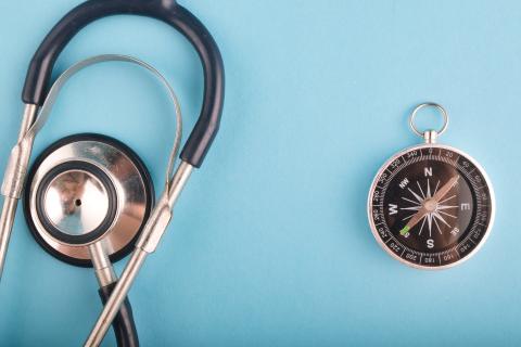 A stethoscope next to a compass on a blue background.