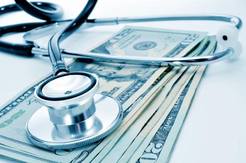 A stethoscope on a small pile of dollar bills. 