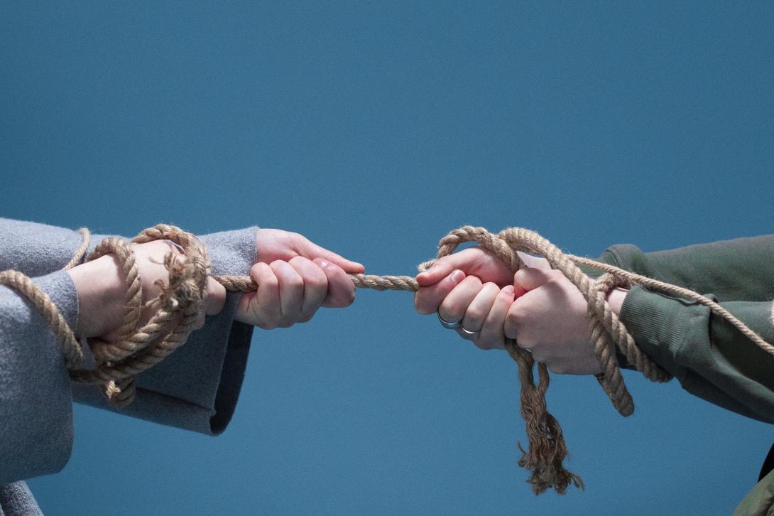Two hands pulling on a rope in a tug of war. 